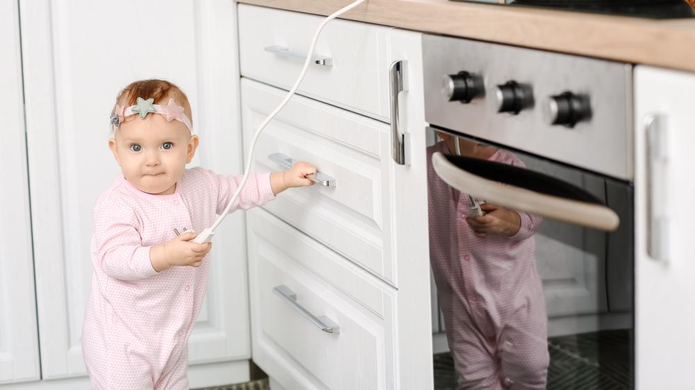 小宝贝玩电插座在厨房。孩子处于危险之中